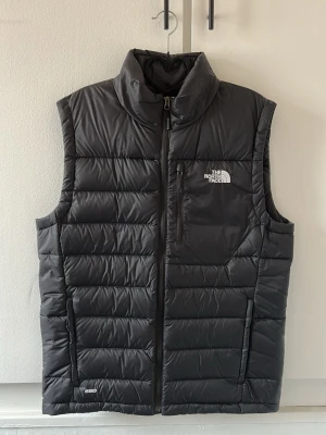 Svart dunväst från The North Face - Svart väst från The North Face. Den är i nyskick, endast använd 1 gång. 