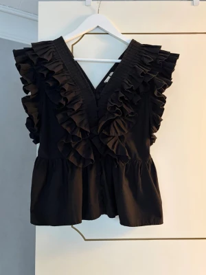 Svart volangblus med v-ringning - Trendig svart blus med volanger som är super söt! 