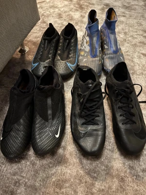 Nike och Adidas fotbollsskor, svart/blå - Säljer flera par fotbollsskor från Nike och Adidas. Skorna är i svart och blått, med moderna, strömlinjeformade designer och syntetmaterial för bästa grepp och bollkontroll. Perfekta för dig som vill ha stilrena och funktionella skor på planen. Blå svarta Nike storlek 38,5 400kr lotto storlek 39,5 300 kr Nike mercurial PRO storlek 42,5 700kr Nike phantom storlek 40 pris 400kr kan köpas som paketpris för 1500