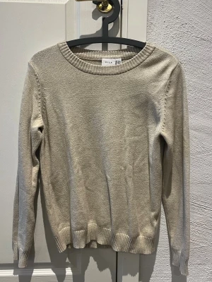 VILA beige tröja, storlek M - Stickad beige VILA tröja med rund halsringning och långa ärmar. Ribbstickade muddar i ärmslut och nederkant. Mycket gott skick! Storlek M