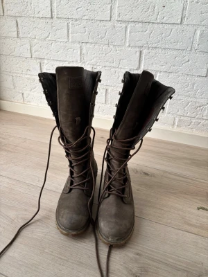 Bruna höga läderstövlar från Helly Hansen  - Säljer ett par bruna höga stövlar från Helly Hansen med snörning hela vägen upp och robust sula. Stövlarna är tillverkade i läder och har en cool, outdoor-inspirerad design med vadderad kant upptill. Perfekta för dig som gillar att sticka ut och vill ha något slitstarkt.