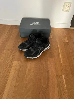 Svarta New Balance sneakers - Snygga svarta sneakers från New Balance med vita detaljer och logga på sidan. Skorna har en sportig design med mesh och syntetmaterial för bra andningsförmåga och komfort. Perfekta för dig som gillar streetwear och en clean look.