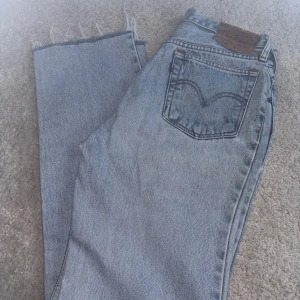 Levi's 510 ljusblå jeans med rå kant - Säljer ett par äldre men klassiska Levi's 510 jeans i ljusblå tvätt. Jeansen har raka ben och en fransig kant nedtill. Perfekta för dig som gillar vintage vibe och tidlös denimstil. Levi's patch bak och femficksmodell. Bra skick bortsätt från läderlappen som skadats lite i tvätt.
