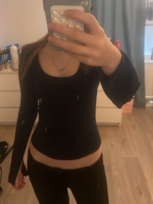 Marinblå långärmad topp med scoop neck - Säljer en svart långärmad topp med snygg scoop neck och tight passform. Perfekt att styla med jeans eller kjol. Ärmarna har tumhål för en cool detalj. Materialet känns mjukt och stretchigt, vilket gör den bekväm att bära hela dagen. Jag säljer den för att den kommer inte till användning. Använd få gånger.