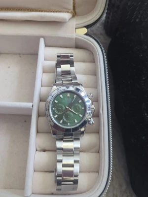 Stilren Klocka, silver - Riktigt snygg R klocka med grön urtavla och silverfärgade detaljer. Tickar inte utan snurrar som den skall, aktiveras när man skakar den. Perfekt för dig som gillar exklusiva accessoarer. Nypris 3699Kr