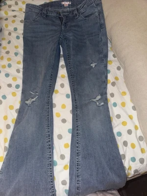 Blå bootcut jeans med broderade fickor från gina tricot - Snygga ljusblå bootcut jeans med slitningar på benen och coola broderade detaljer på bakfickorna. Klassisk femficksmodell och bekväm passform. Perfekta för dig som gillar en avslappnad och trendig look.