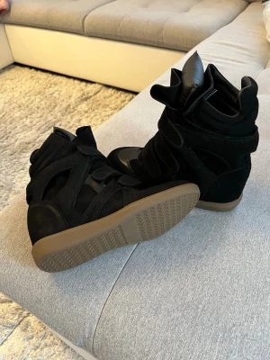 Isabel marant - Säljer ett par Isabel marant. Skorna har en cool, sportig design med detaljer i mocka och syntet samt en beige sula. Perfekta för dig som vill ha både höjd och streetstyle-vibe.