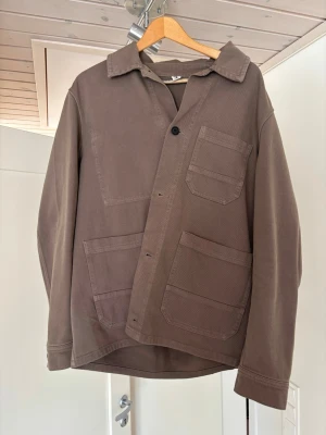 Overshirt Arket - Säljer en olivgrön overshirt från Arket i kraftig bomull i storlek 50 (dvs M) med tre stora påsydda fickor framtill och klassisk krage. Jackan har raka ärmar och stängs med svarta knappar. Perfekt för lager-på-lager och en clean look på våren. Priset går att diskutera!