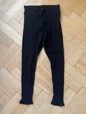 Svarta ribbade leggings med hög midja - Säljer ett par svarta leggings med ribbad struktur och hög midja. De är stretchiga och sitter tight, perfekta för en chill look. 