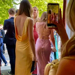 Ljusrosa balklänning med snörning - Säljer en elegant ljusrosa långklänning med snörning i ryggen och omlott-detaljer. Klänningen har en tight passform och är ärmlös, perfekt för balen. Endast använd vid ett tillfälle.