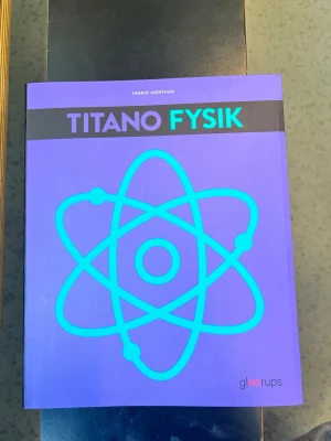 Titano Fysik Gleerups - Titano Fysik är en kursbok i fysik för årskurs 7-9, skriven av Ingrid Monthan. Boken har ett lila omslag med en stor blå atom-symbol på framsidan. Den är tryckt på papper och har tydliga färgdetaljer och modern design. Perfekt för dig som pluggar fysik i grundskolan.