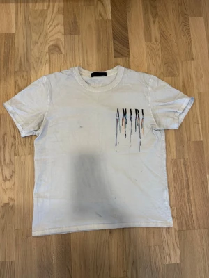  AMIRI t-shirt  - Säljer en vit t-shirt från AMIRI med coolt tryck på bröstet där bokstäverna har färg som rinner ner. Klassisk rund hals och korta ärmar. Perfekt för dig som gillar streetwear. tröjan har defekter och är lite smutsig och jag vet inte om det går bort med tvättning men som ni kan se hur den sitter på mig.