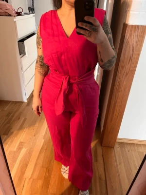 Jumpsuit strl L Mango  - Rosa jumpsuit strl L från Mango. Material: 100% linne. Dragkedja i ryggen, knytning framtill. 