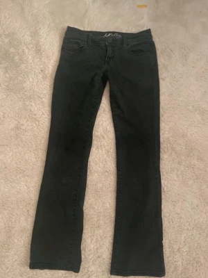 Svarta bootcut jeans - Säljer ett par svarta bootcut jeans från L.O.G.G. Jeansen har klassisk femficksdesign, knapp och dragkedja framtill samt bakfickor med lock och knapp. Materialet är mjukt denim med lite stretch för skön passform.
