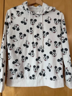 hoodie med Mickey Mouse - Cool vit hoodie från Disney med all-over print av Mickey Mouse-ansikten i svart och rött. 