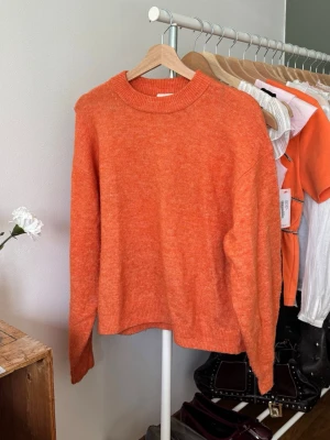 Orange stickad tröja med rund hals - Mysig orange stickad tröja med avslappnad passform och rund halsringning. Har tyvärr blivit lite nopprig 