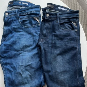 Replay Anbass jeans blå, stl 32 - Två par Replay Anbass jeans i olika blå tvättar. Klassisk femficksmodell med snygga detaljer och läderpatch bak. Jeansen har normal passform och raka ben, tillverkade i mjuk bomullsdenim med lite stretch för extra komfort.  Kan sälja alla tre par för 600kr men säljer ett par för 250 kr