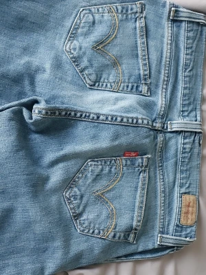 Ljusblå Levi's 504 jeans - Säljer ett par ljusblå Levi's 504jeans med klassiska fem fickor och snygga kontrastsömmar på bakfickorna. Jeansen har normal midja, raka ben och är tillverkade i bomull. Perfekta för en avslappnad och trendig look.