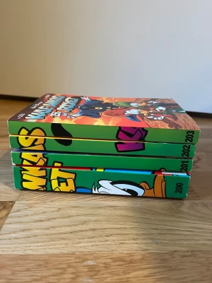 Kalle Anka Pocket nr 200-203 - Fyra färgglada pocketböcker från Kalle Anka-serien, nummer 200 till 203.  Böckerna är i pocketformat och tryckta på papper. Säljer 20 kr styck eller alla för 60 kr 