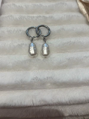 Silvriga hoops med vita pärlor🌸 - Säljer ett par stilrena örhängen med silvriga hoops och droppformade vita pärlor. Perfekta för dig som gillar en enkel men elegant look. Passar till många olika stilar och är lätta att matcha med andra smycken.💕 Alla smycken på sista bilden finns att köpa i både silver och guld