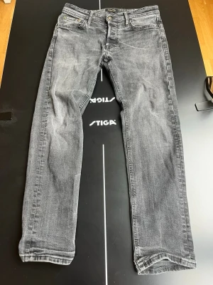 Grå raka jeans med slitningar - Snygga grå jeans med raka ben och diskreta slitningar. Klassisk femficksmodell med knapp och dragkedja framtill. Jeansen har en tvättad look och är tillverkade i denim, perfekt för en avslappnad stil.