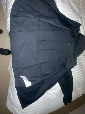 Svart hoodie med huva - En enkel svart hoodie med huva, tillverkad i mjukt material. Hoodien har långa ärmar och klassisk passform, perfekt för dig som gillar en clean och stilren look. Passar bra till jeans eller joggers.