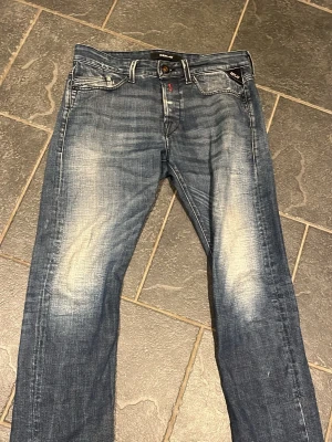 Replay jeans - Säljer ett par blå jeans med snyggt slitna detaljer och raka ben. Jeansen har klassisk femficksdesign och ljusare partier på lår och knän för en trendig, använd look. Perfekta för en avslappnad stil. Sparsamt använda i storlek 30 w 32 l.  Replay jeans