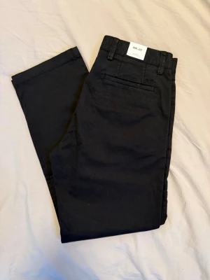 Svarta chinos från NN07 - Helt oanvända svarta chinos från NN07 med lapparna kvar, modell Alex med straight fit. Storlek 32/32.