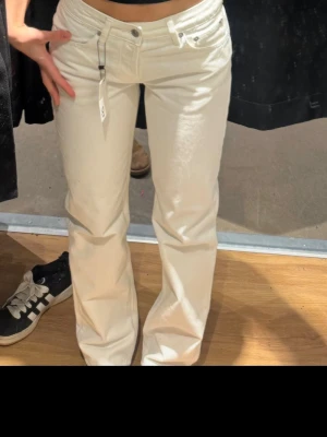 Vita raka jeans  - Säljer ett par snygga vita jeans från lager med rak passform och klassisk femficksdesign. Jeansen har normal midja och är tillverkade i ett mjukt bomullsmaterial. Perfekta för dig som vill ha en clean och fräsch look. 