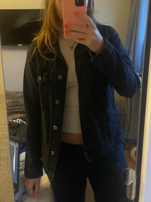 Svart jeansjacka med silverknappar - Säljer en svart jeansjacka med klassisk rak passform och silverfärgade knappar. Jackan har två bröstfickor med lock och knapp samt sömdetaljer framtill. I ett väldigt bra skick och perfekt nu till våren❣️