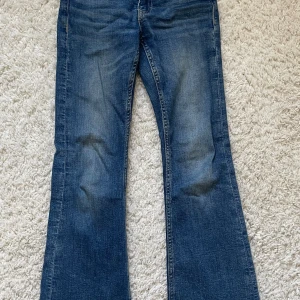 Blå bootcut jeans  - Säljer ett par klassiska blå bootcut jeans från 7 For All Mankind. Jeansen har en snygg passform och coola fickor. Perfekta för dig som gillar en avslappnad men trendig look.