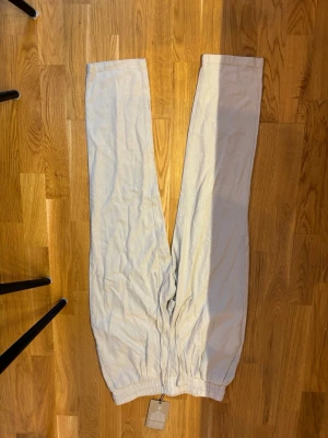 Beige linnebyxor med resår - Säljer ett par beige linne byxor  med resår i midjan och vid bensluten. Byxorna har en avslappnad passform och är tillverkade i ett mjukt och bekvämt material. Perfekta för chill dagar hemma eller när du vill ha det extra bekvämt. Storlek xs