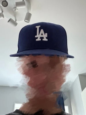 Blå LA Dodgers keps från New Era - Snygg blå keps från New Era med LA Dodgers-logga broderad i vitt framtill och New Era-logga på sidan. Klassisk rak skärm och djup passform. Perfekt för dig som vill ha en sportig och trendig look. Materialet är tåligt och kepsen har ventilerande hål upptill.
