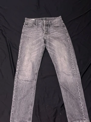 Grå loose fit jeans Jack & Jones - Säljer ett par grå loose fit jeans från Jack & Jones, modell LOOSE/CHRIS. Jeansen har raka ben, klassisk femficksdesign och är tillverkade i denim med tvättad look. Perfekta för en avslappnad och trendig stil.