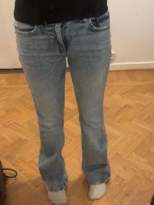 Ljusblå bootcut jeans - Säljer ett par ljusblå bootcut jeans med klassisk femficksdesign och normal midja. Jeansen har en avslappnad passform över låren och lätt utsvängda ben. Perfekta för en casual och trendig look.