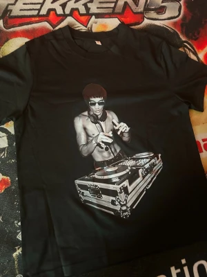 Svart t-shirt med Bruce Lee-print - Cool svart t-shirt med tryck av Bruce Lee vid mixerbord på framsidan. T-shirten har rund hals och korta ärmar. Perfekt för dig som gillar musik och streetwear vibes.
