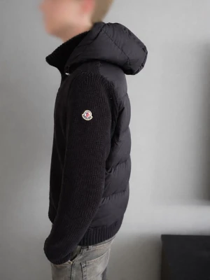 Moncler Cardigan - Säljer min svarta Moncler cardigan med huva. Sjukt snygg modell med stickade ärmar och framtill samt dun/puffer på ryggen och på huvan. Perfekt som vår-, höstjacka eller som ett exklusivt lager på vintern.  Använd fåtal gånger och i mycket fint skick utan större tecken på användning. Dragkedjor och detaljer är i toppskick.  Storlek: S Färg: Svart pris: 2299kr  Skriv gärna vid frågor eller om du vill ha fler bilder 💬