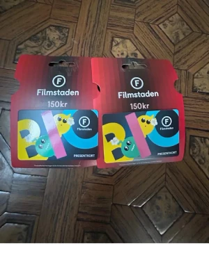 Filmstaden presentkort 150kr - Två presentkort från Filmstaden, värde 150kr styck. Kortet har färgglad design med texten BIO och tecknade figurer i gult, grönt och rosa. Perfekt för biobesök och upplevelser.