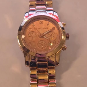 Guldig klocka från Michael Kors - Stilren guldklocka som lyfter varje outfit ✨ Perfekt till både vardag & fest. 👩 Kön: Dam ✨ Klassisk design i guld 📅 Datumvisning & kronograf 🔗 Justerbart armband 💛 Fint helhetsintryck 📦 Snabb leverans #klocka #michaelkors #dam #guld #nytt batteries behövs 