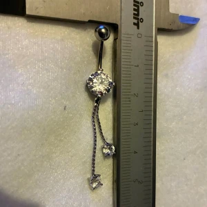 ✨ NY oanvänd navelpiercing med hänge - Kirurgiskt stål 316L  - ✨ NYTT oanvänt smycke i kirurgiskt stål! 🌸 Hållbart & Rostfritt: Slitstarkt 316L-stål som inte oxiderar eller rostar av fukt. 🌸 Säkert: Industristandard, skonsamt för läkta piercingar.  🛍️ 30 % BUNDLE-RABATT! Köp fler artiklar från min shop och få 30 % på allt! ✨ 📦 Frakt: Endast spårbart via Plick SafePay för vår trygghet.