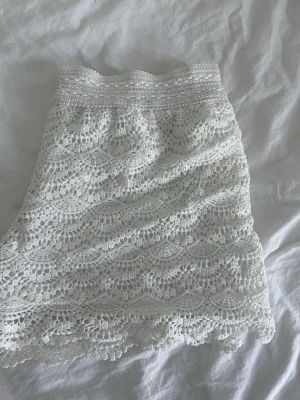 Vita Spetsshorts  - Säljer en söt vita shorts i spets med fina virkade detaljer och volangkant. Perfekt att styla med en enkel topp för en fräsch look. Passar perfekt nu till vår/sommar. Skriv om ni har några funderingar. Står storlek S/M men skulle säga storlek L. ( säljer då de inte passar mig )