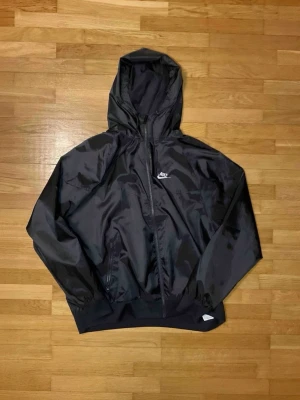 Svart Nike Windbreaker  - Säljer min svarta Nike windbreaker eftersom den är för stor på mig. Den är i bra sick med inga fläckar eller skador på den.