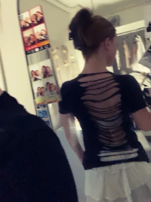 Svart t-shirt med slitsad rygg - Cool svart t-shirt med korta ärmar och öppen, slitsad rygg som ger en edgy look. Perfekt för dig som vill sticka ut och addera lite attityd till din outfit. Passar snyggt till både jeans och kjol.