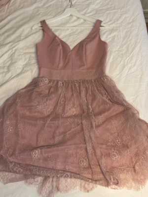 Rosa spetsklänning med v-ringning - Supersöt rosa klänning med v-ringad överdel. Kjolen är i flera lager med vacker spetsdetalj.   Från MOHITO