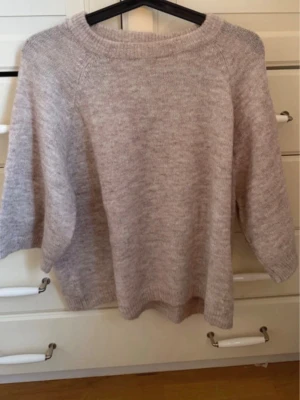 Ljusbeige stickad tröja 157 XS - Mysig ljusbeige stickad tröja från 157 i storlek XS. Tröjan har rund halsringning och är gjord i ett mjukt, fluffigt material som känns skönt mot huden. Perfekt för lager på lager och enkel att matcha med olika outfits.