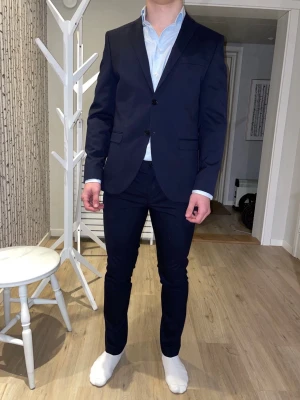 Kostym/exsamenskläder + skjorta - Säljer en kostym inklusive skjorta från märket Selected Homme. Kostymen slimfit i färgen marinblå och skjortan slim fit ljusblå. Hela setet är använda endast 1 gång så är i princip helt nytt utan tecken på användning! Storleken på kavaj - 46 Storleken på skjortan - 38 Storleken på byxorna - 48 I helhet skulle jag säga att storlekarna är en större S eller en mindre M.  Hör av dig vid frågor eller funderingar!😊