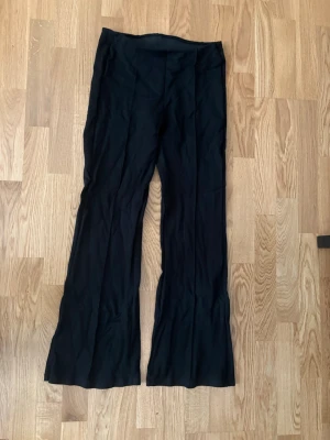 Svarta utsvänga byxor - Säljer ett par svarta byxor från Kappahl i storlek S. De har utsvängda ben och är tillverkade i ett mjukt och stretchigt material som sitter skönt på kroppen. 