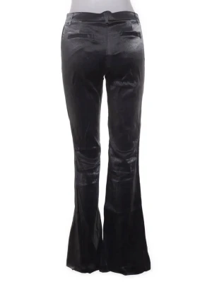 Svarta utsvängda kostymbyxor - Snygga svarta kostymbyxor med utsvängda ben och pressveck. Byxorna har fickor bak och bälteshällor i midjan. Materialet har en lätt glansig finish som ger en cool look. Perfekta för dig som vill ha en trendig och stilren vibe.