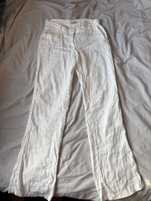 Vita linnebyxor från Nelly - Säljer ett par vita linnebyxor med låg midja. Byxorna har fickor fram och är gjorda i ett luftigt linnetyg som passar perfekt till sommaren.