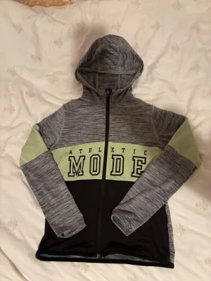 Träningskofta - Träningskofta från H&M i stlk 130/140, yttertyg i 91% polyester och 9% elastan, paneler i 92% polyester och 8% elastan